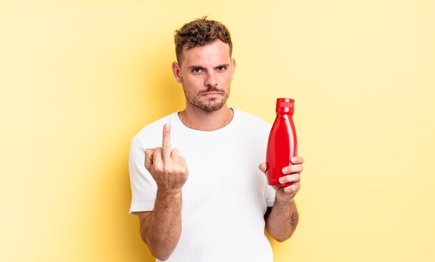 Hombre guapo joven que se siente enojado, molesto, rebelde y agresivo. concepto de salsa de tomate