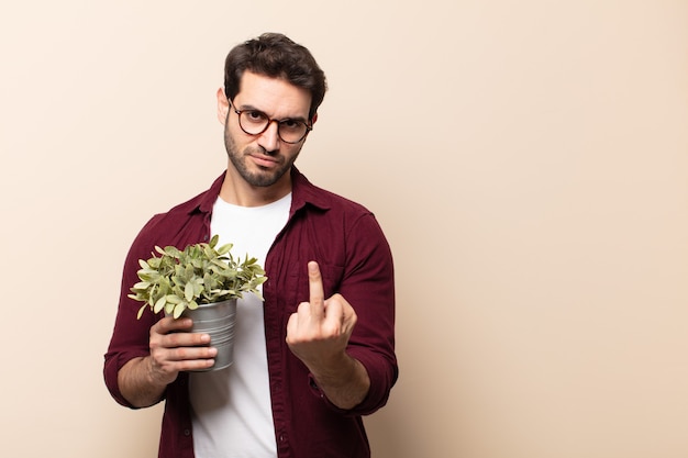 Hombre guapo joven que se siente enojado, molesto, rebelde y agresivo, moviendo el dedo medio, contraatacando