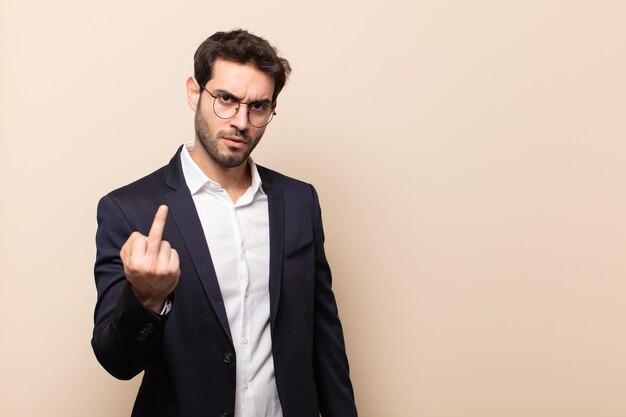 Hombre guapo joven que se siente enojado, molesto, rebelde y agresivo, moviendo el dedo medio, contraatacando