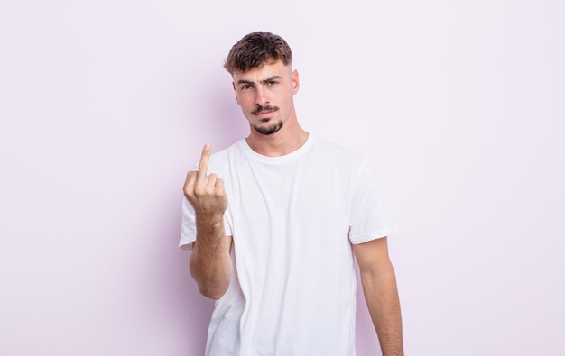 Hombre guapo joven que se siente enojado, molesto, rebelde y agresivo, moviendo el dedo medio, contraatacando