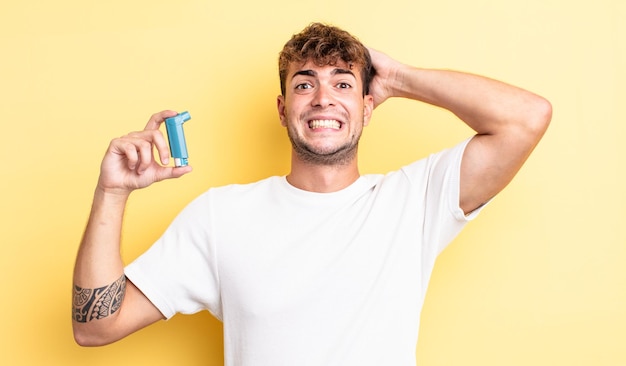 Hombre guapo joven que se siente estresado, ansioso o asustado, con las manos en la cabeza. concepto de asma