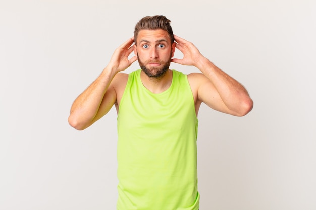 Hombre guapo joven que se siente estresado, ansioso o asustado, con las manos en la cabeza. concepto de fitness