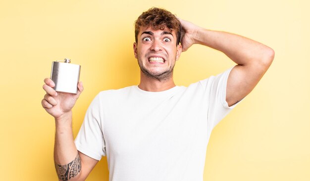 Hombre guapo joven que se siente estresado, ansioso o asustado, con las manos en la cabeza. concepto de matraz de alcohol