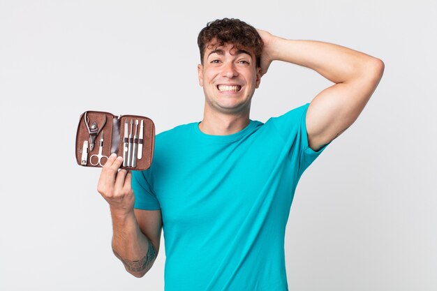 Hombre guapo joven que se siente estresado, ansioso o asustado, con las manos en la cabeza y sosteniendo un estuche de herramientas de uñas