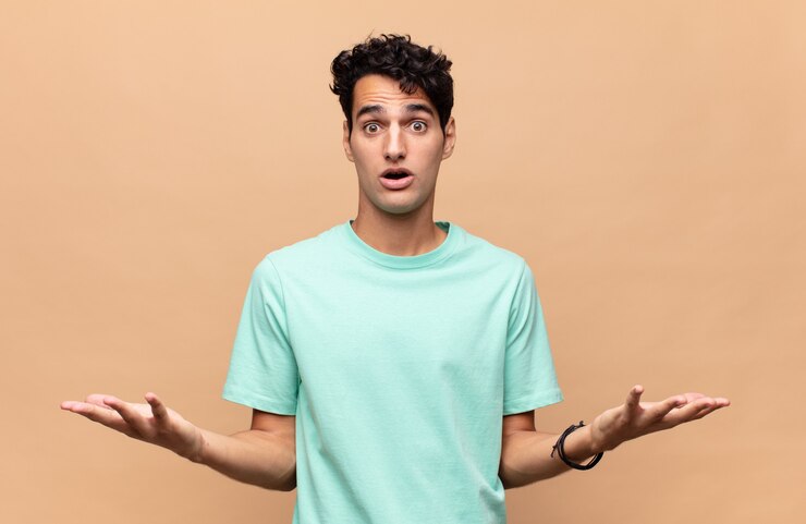 Foto hombre guapo joven que se siente extremadamente conmocionado y sorprendido, ansioso y en pánico, con una mirada estresada y horrorizada