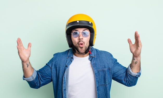 Hombre guapo joven que se siente extremadamente conmocionado y sorprendido. concepto de casco de moto