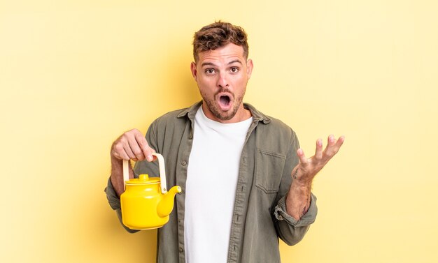 Hombre guapo joven que se siente extremadamente conmocionado y sorprendido. concepto de tetera