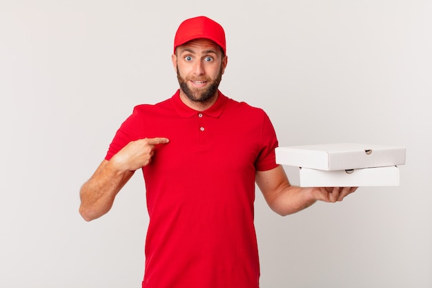 Hombre guapo joven que se siente feliz y apunta a sí mismo con un emocionado. concepto de entrega de pizza