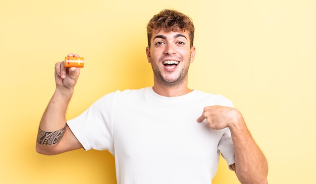 Hombre guapo joven que se siente feliz y apuntando a sí mismo con un emocionado con una batería