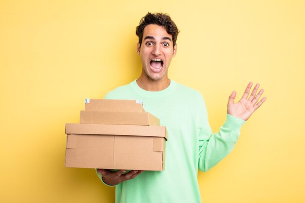 Hombre guapo joven que se siente feliz y asombrado por algo increíble cajas de paquetes