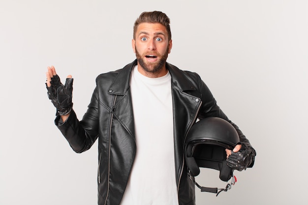 Hombre guapo joven que se siente feliz y asombrado por algo increíble. concepto de casco de moto