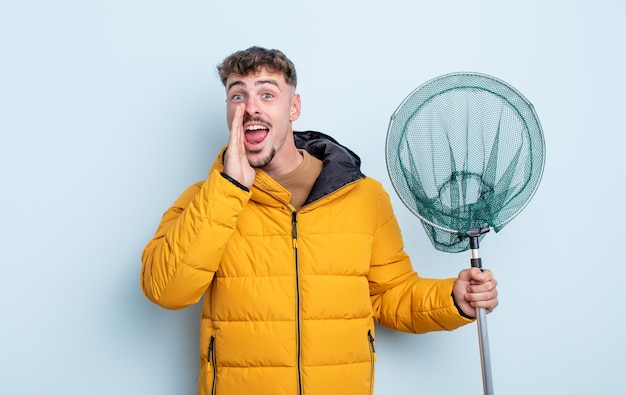 Hombre guapo joven que se siente feliz, dando un gran grito con las manos al lado de la boca. concepto de pescador