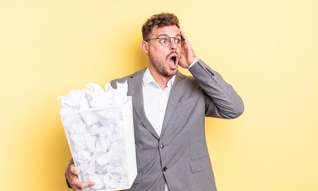 Hombre guapo joven que se siente feliz, emocionado y sorprendido concepto de basura de bolas de papel