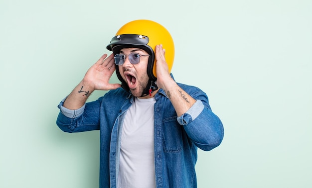 Foto hombre guapo joven que se siente feliz, emocionado y sorprendido. concepto de casco de moto