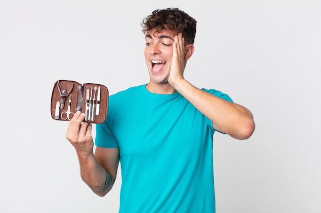 Hombre guapo joven que se siente feliz, emocionado y sorprendido y sosteniendo una caja de herramientas de uñas