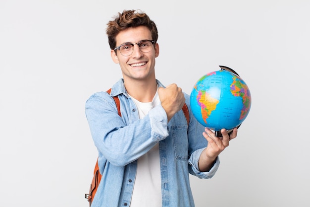 Hombre guapo joven que se siente feliz y enfrenta un desafío o celebra. estudiante sosteniendo un mapa del globo terráqueo