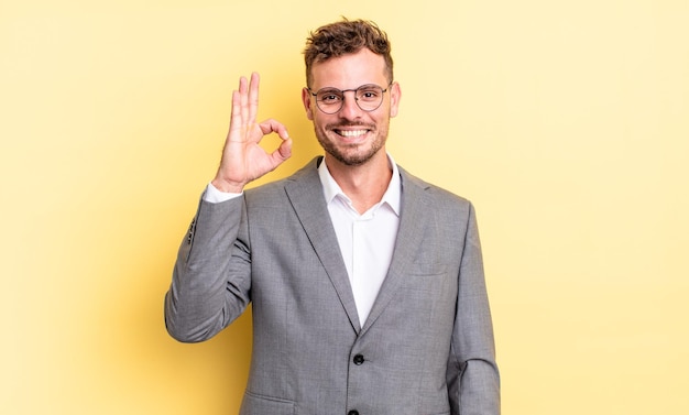 Hombre guapo joven que se siente feliz mostrando aprobación con el concepto de negocio de gesto bien