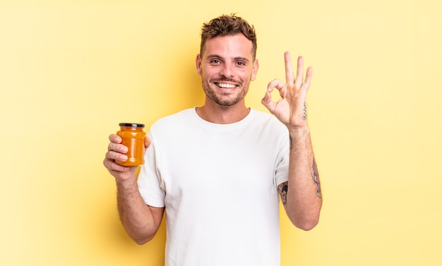 Hombre guapo joven que se siente feliz, mostrando aprobación con gesto bien. concepto de gelatina de durazno