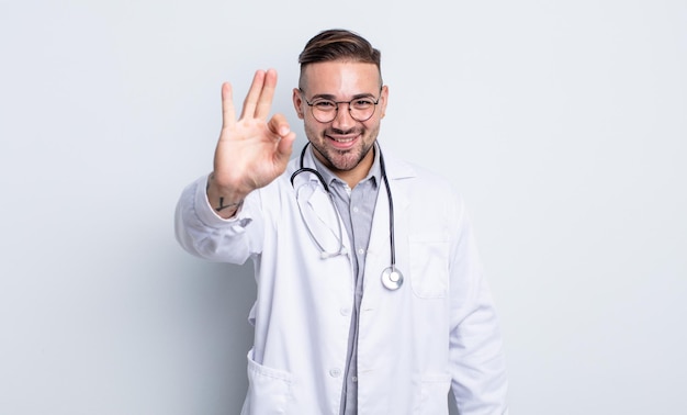 Hombre guapo joven que se siente feliz, mostrando aprobación con gesto bien. concepto médico