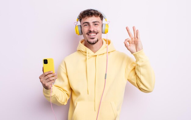 Hombre guapo joven que se siente feliz, mostrando aprobación con un gesto bien. concepto de musica