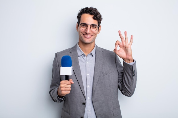 Hombre guapo joven que se siente feliz, mostrando aprobación con gesto bien. presentador con micrófono