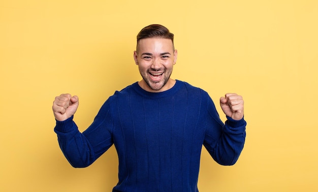 Hombre guapo joven que se siente feliz, positivo y exitoso, celebrando la victoria, los logros o la buena suerte