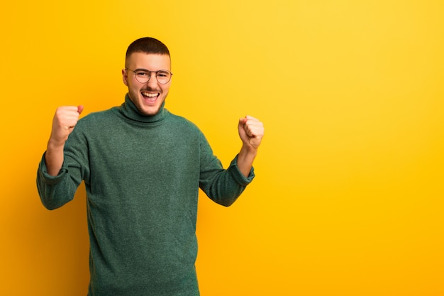 Hombre guapo joven que se siente feliz, positivo y exitoso, celebrando la victoria, los logros o la buena suerte