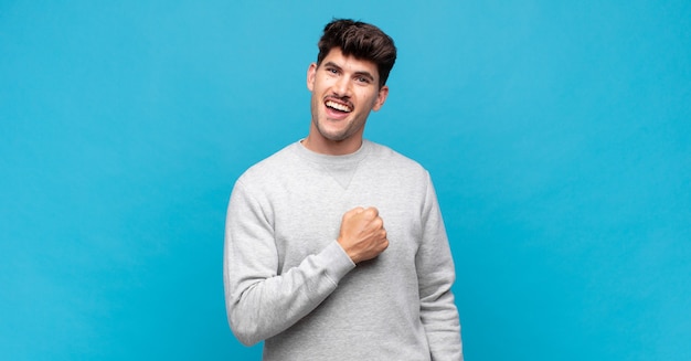 Hombre guapo joven que se siente feliz, positivo y exitoso, motivado cuando enfrenta un desafío o celebra buenos resultados