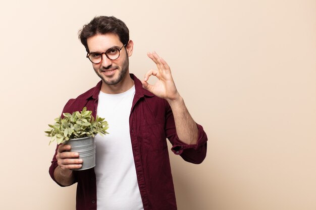 Hombre guapo joven que se siente feliz, relajado y satisfecho, mostrando aprobación con gesto bien, sonriendo