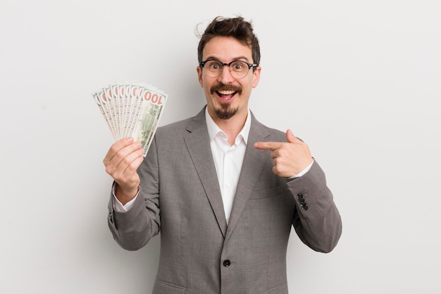 Hombre guapo joven que se siente feliz y se señala a sí mismo con un hombre de negocios emocionado y billetes