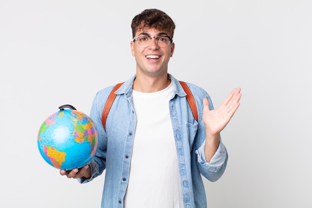 Hombre guapo joven que se siente feliz, sorprendido al darse cuenta de una solución o idea. estudiante sosteniendo un mapa del globo terráqueo