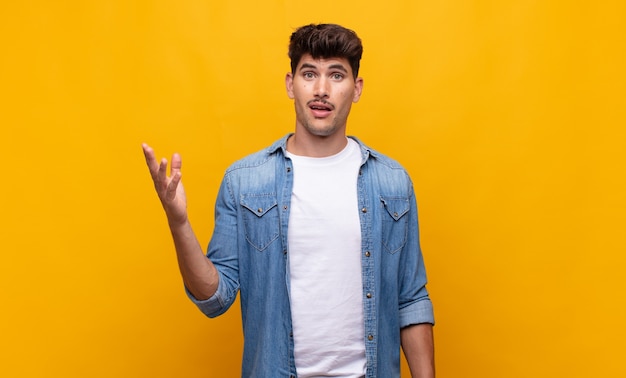 Hombre guapo joven que se siente feliz, sorprendido y alegre, sonriendo con actitud positiva, dándose cuenta de una solución o idea