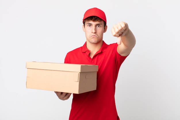 Hombre guapo joven que se siente mostrando los pulgares hacia abajo el concepto de servicio de paquete de entrega