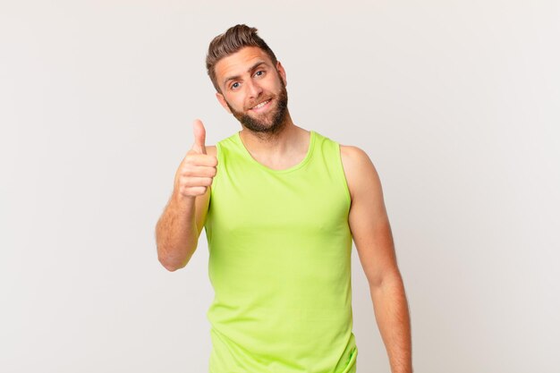 Hombre guapo joven que se siente orgulloso sonriendo positivamente con los pulgares hacia arriba concepto de fitness