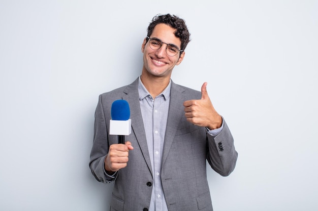 Hombre guapo joven que se siente orgulloso, sonriendo positivamente con los pulgares hacia arriba. presentador con micrófono