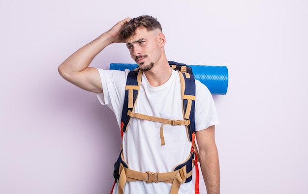 Hombre guapo joven que se siente perplejo y confundido, rascándose la cabeza. concepto de excursionista