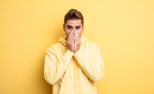 Hombre guapo joven que se siente preocupado, molesto y asustado, cubriendo la boca con las manos, luciendo ansioso y habiéndose estropeado. extraño concepto de bigote