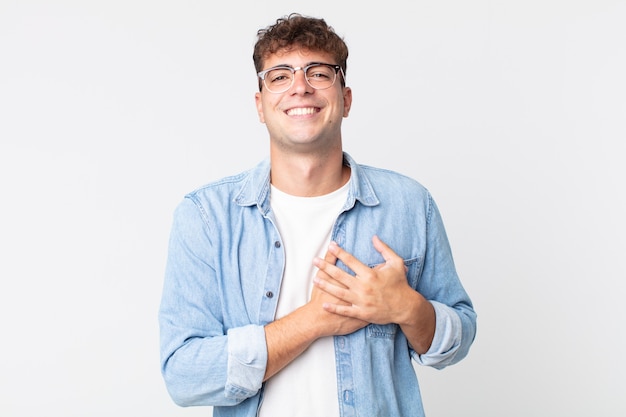 Hombre guapo joven que se siente romántico, feliz y enamorado, sonriendo alegremente y tomados de la mano cerca del corazón