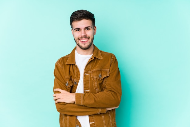 Hombre guapo joven que se siente seguro, cruzando los brazos con determinación.