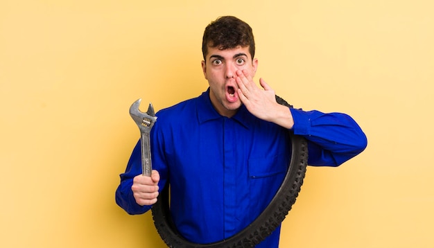 Hombre guapo joven que se siente sorprendido y asustado concepto de reparador de bicicletas