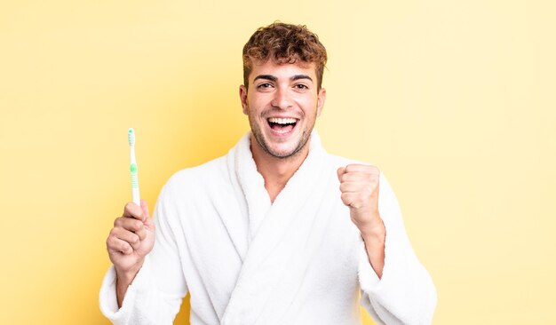 Hombre guapo joven que se siente sorprendido, riendo y celebrando el éxito. concepto de cepillo de dientes