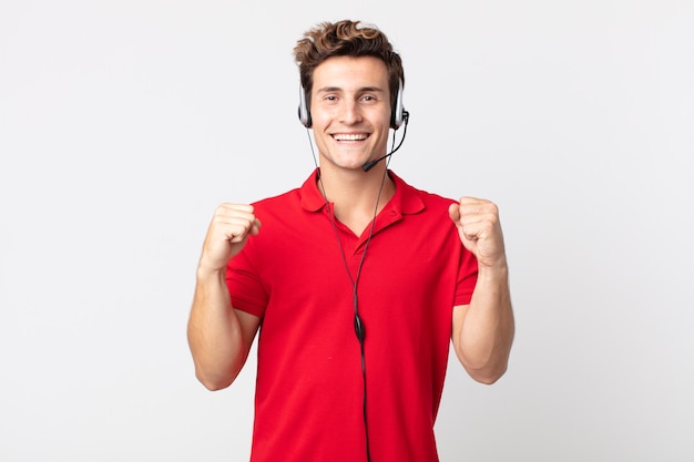 Hombre guapo joven que se siente sorprendido, riendo y celebrando el éxito. concepto de telemarketer