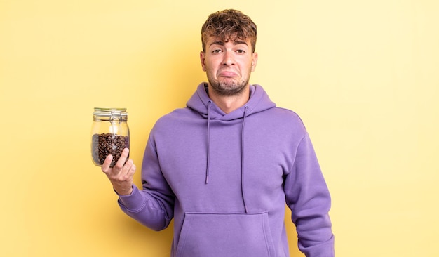 Hombre guapo joven que se siente triste y llorón con una mirada infeliz y llorando. concepto de granos de cafe