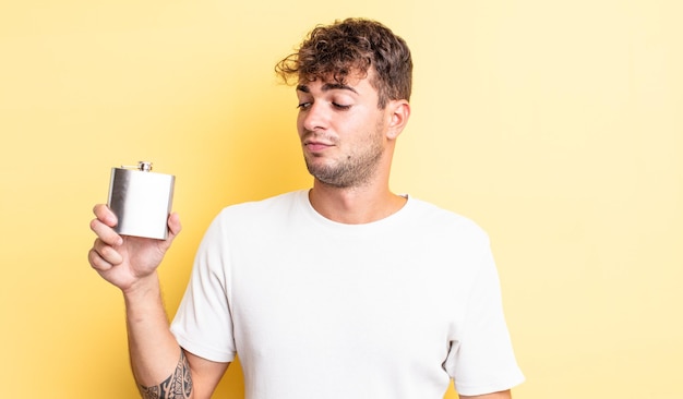 Hombre guapo joven que se siente triste, molesto o enojado y mirando hacia un lado. concepto de matraz de alcohol