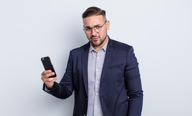 Hombre guapo joven que se siente triste, molesto o enojado y mirando hacia el lado del negocio y el concepto de teléfono inteligente