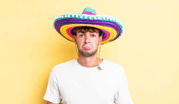 Hombre guapo joven que se siente triste y quejumbroso con una mirada infeliz y llorando. concepto de sombrero mexicano