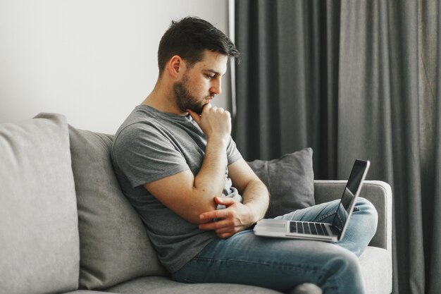 Hombre guapo joven que trabaja en su computadora portátil