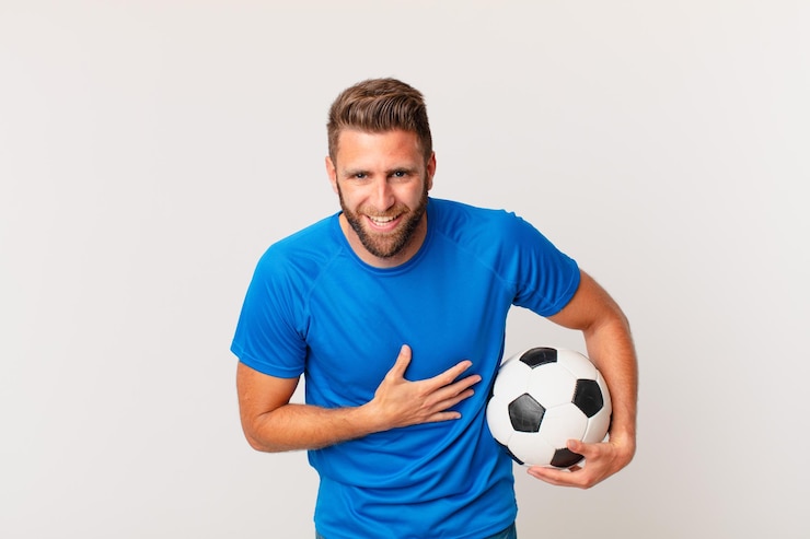 Foto hombre guapo joven riendo a carcajadas de una broma hilarante. concepto de futbol