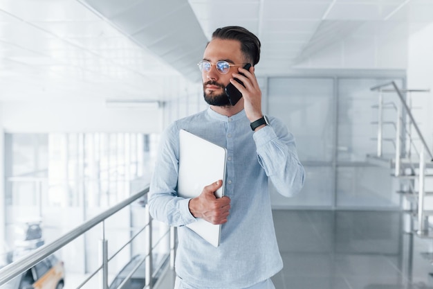 Hombre guapo joven con ropa formal en el interior de la oficina durante el día