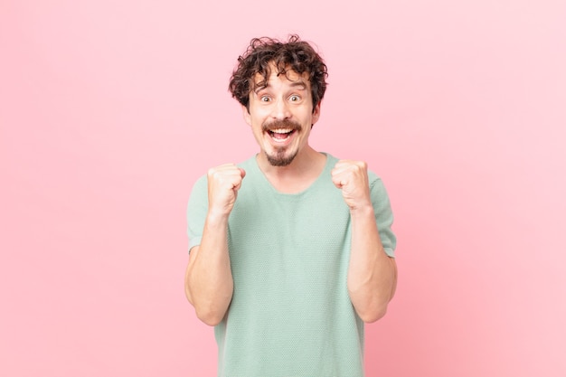 Hombre guapo joven sintiéndose conmocionado, riendo y celebrando el éxito